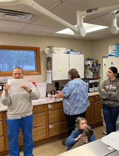 Three women and a child in a veterinary clinic, one woman reading a document.
