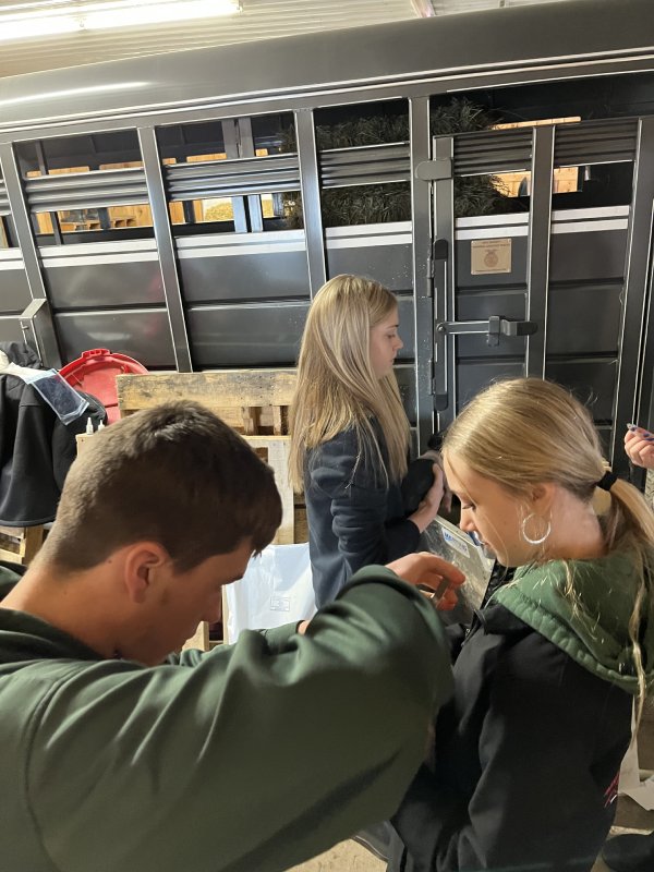 Three people examining items in lockers at a busy location.